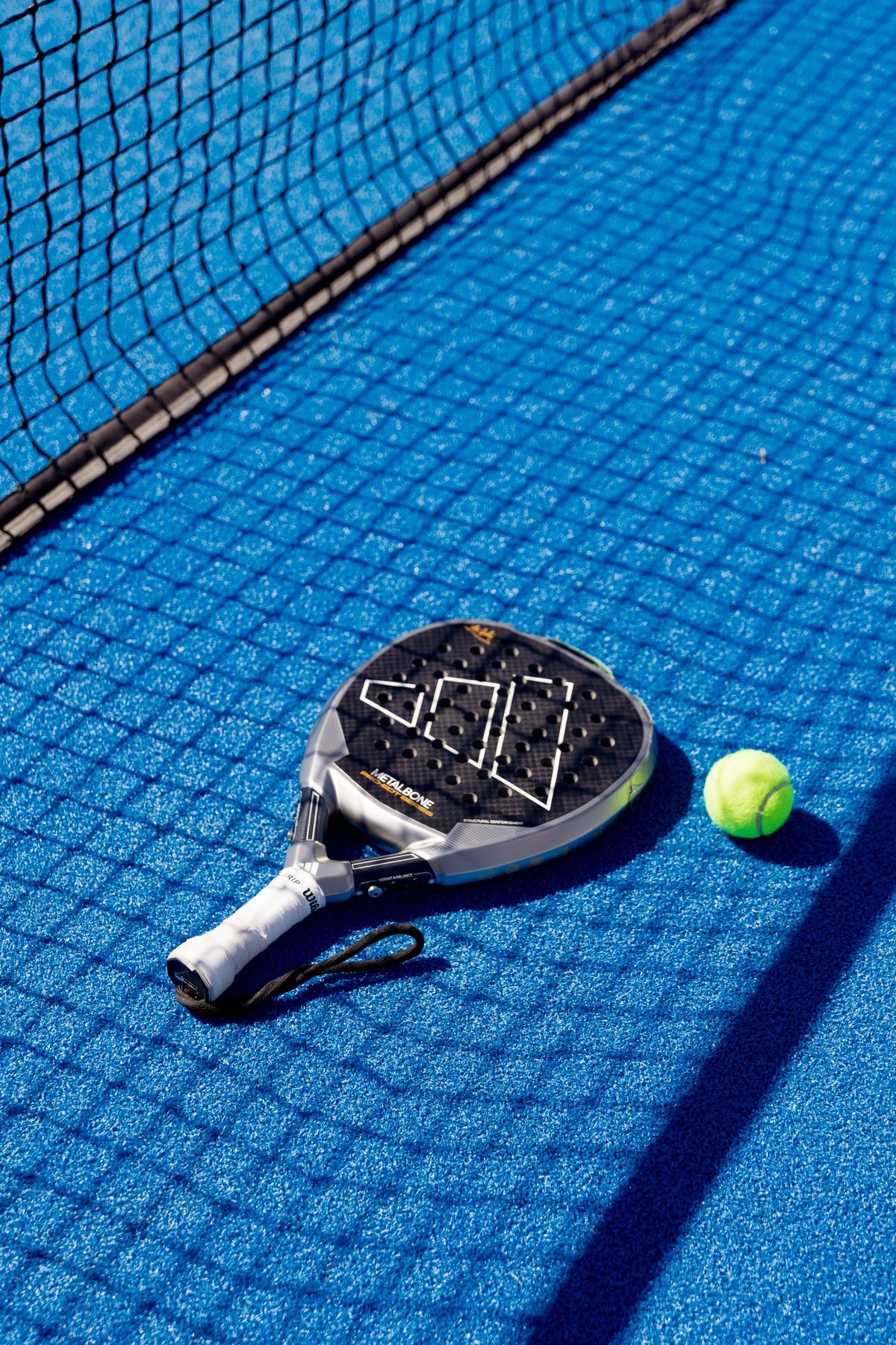 Racchetta da padel e pallina sul campo blu
